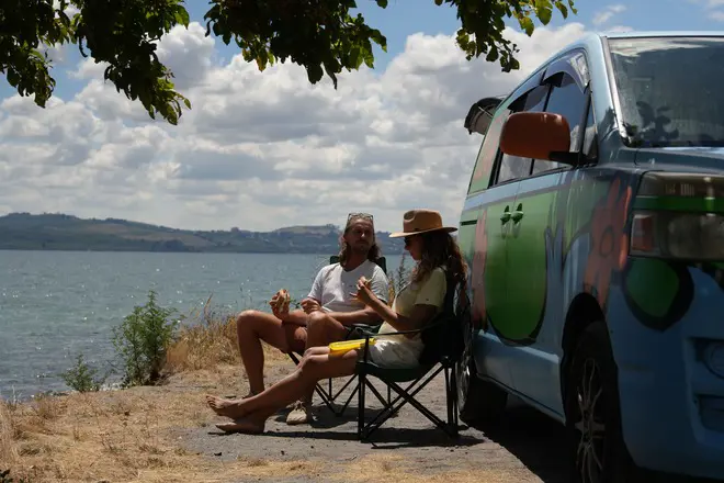Couple relaxing beside a Mystery Machine campervan overlooking Lake Taupo